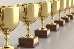 Linear Array of Gold Trophys on a Light Gray Surface